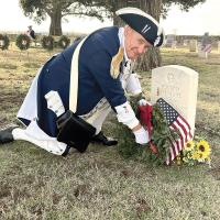 Henry Baer places a wreath by a veteran’s tombstone