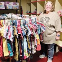 Connie Chambless stands next to children’s clothing inside the Love for the Children Center