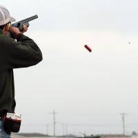 Baylor Heinrich watches a load of buckshot (center dot) fly toward an orange clay target as the shell ejects from his shotgun