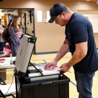 Darrin Peffer inserts one of his ballots into a voting machine