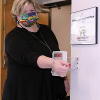 Sheryl Barnett tries out the new touchless temperature scanner