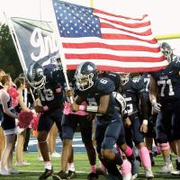 Elijah Fisher (6) carries the American flag onto the field