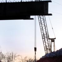 Construction workers fight the setting sun for light