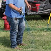 John Cochran sprays blue-colored weed killer around a drainage opening