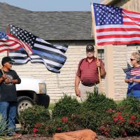 Fred Horn, Diane Birdsong and an unidentified war veteran hold flags