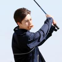 Brian Richardson holds a sandwich in his mouth while hitting a tee shot