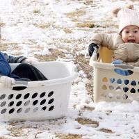 David and Asahi Paris use laundry baskets to slide down the hill