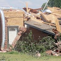 A storm repairman inspects a damaged home
