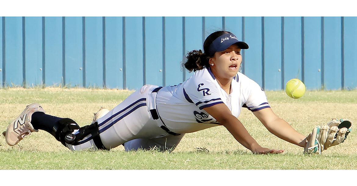Harmoni Moore slides headfirst on the grass as she tries to catch a fly ball_slideshow