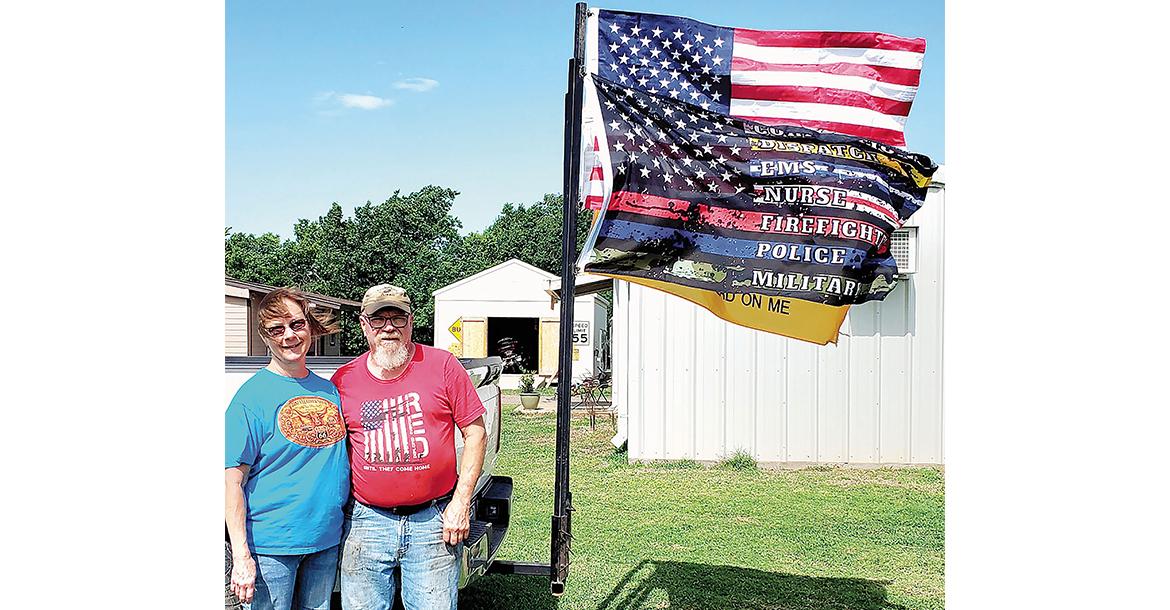 Floyd and Toni Mullens pose next to the flag that greeted first responders_slideshow