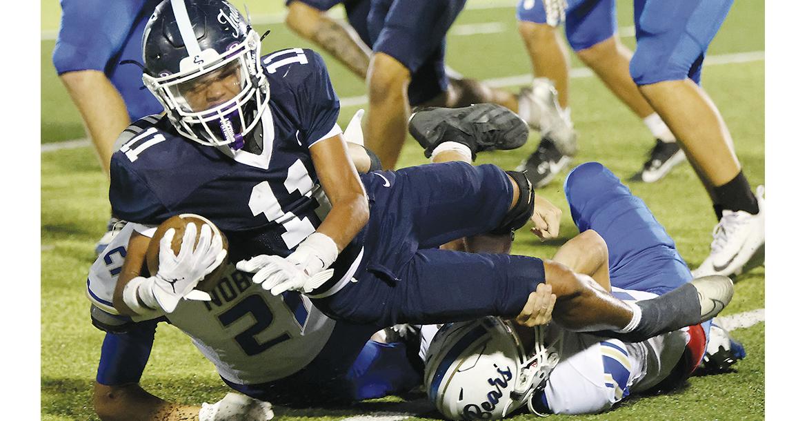 Bentley Evans leans over two Noble tacklers to gain extra yards_slideshow