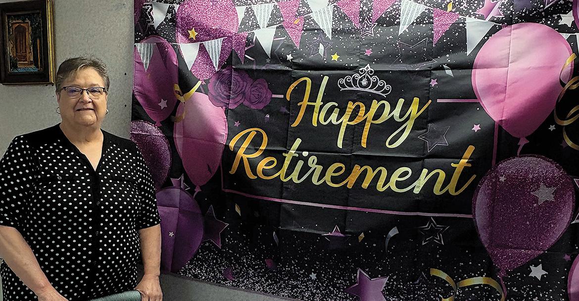 Becky Wahler stands next to her retirement party banner_slideshow