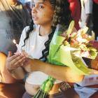 Antoinette Richey holds a bouquet of flowers and a lighted candle during the vigil