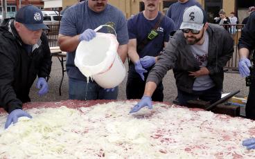Matt Sandidge (far right) helps spread out onions on top of the hamburger meat
