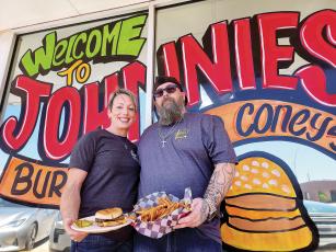 Lacey and William Brickey hold up an onion burger and fries