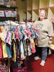 Connie Chambless stands next to children’s clothing inside the Love for the Children Center