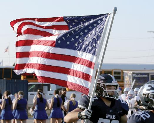 Cade Houston carries the American flag onto the field