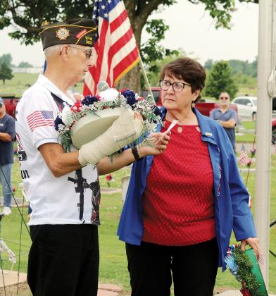 Nancy Salsman holds the microphone while Cliff Cagle of the VFW prepares to lay a wreath