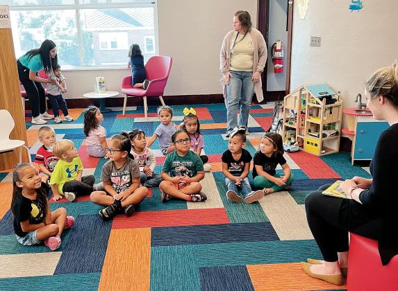 Children sit and listen as Bridget Scheffler reads them a story