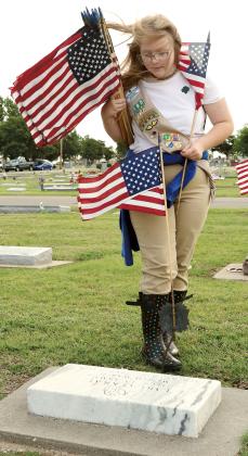 Madison Bigger helps place flags on the gravesite of a veteran