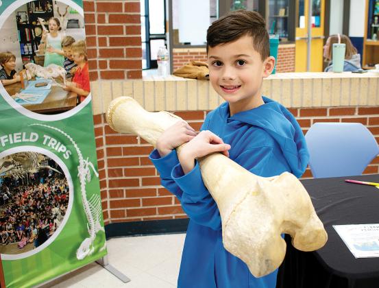 Landon Findley holds up a massive bone from an elephant