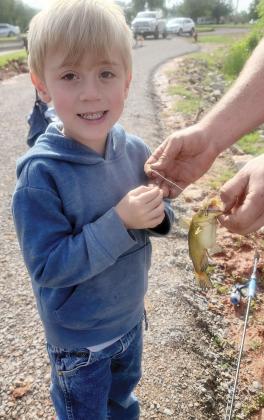 Rhiller Ellison smiles as he gets help holding up a small bass