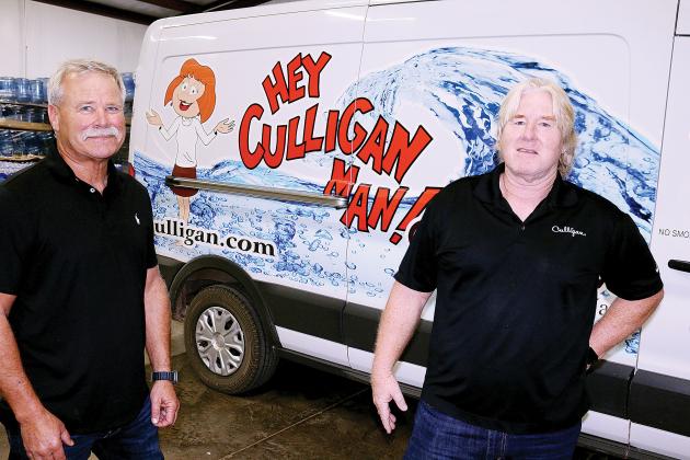 Brian and Greg Mollman stand next to one of the delivery vehicles their business uses to deliver water