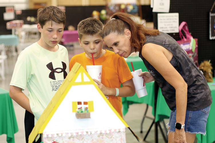 Shawna Oakes of El Reno looks over one of the arts and crafts entries with sons, Philip and Jacob