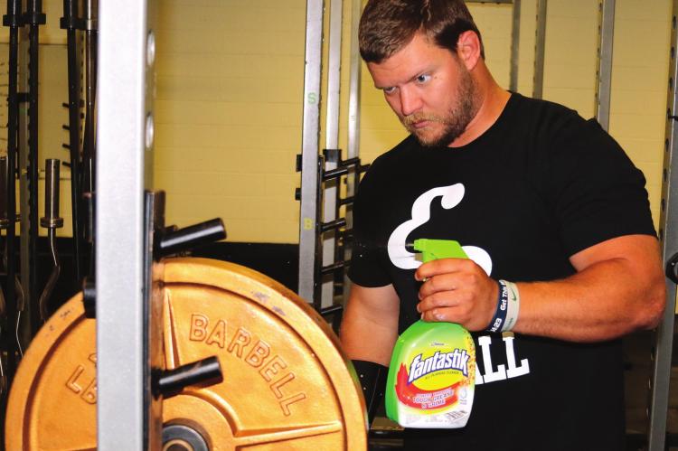 Austin Feddersen sprays down disks in the weight room