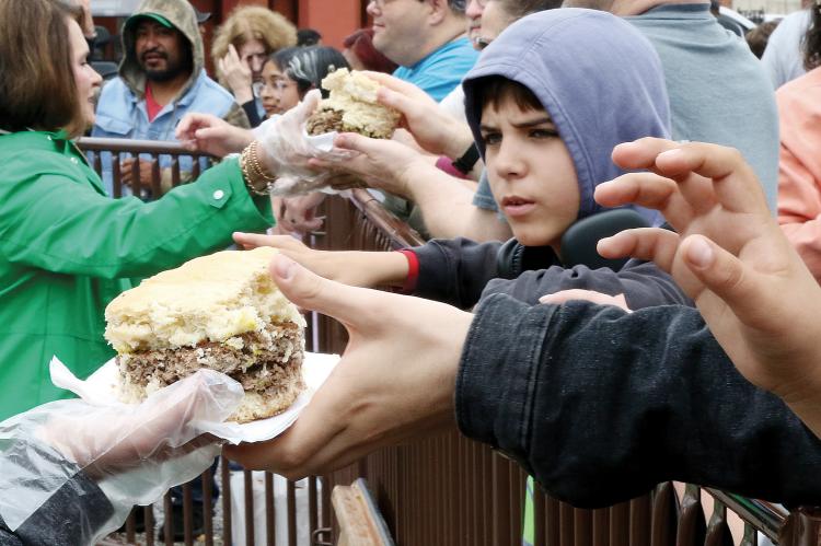 The crowd lines the barriers hoping to get a slice of the world’s largest fried onion burger