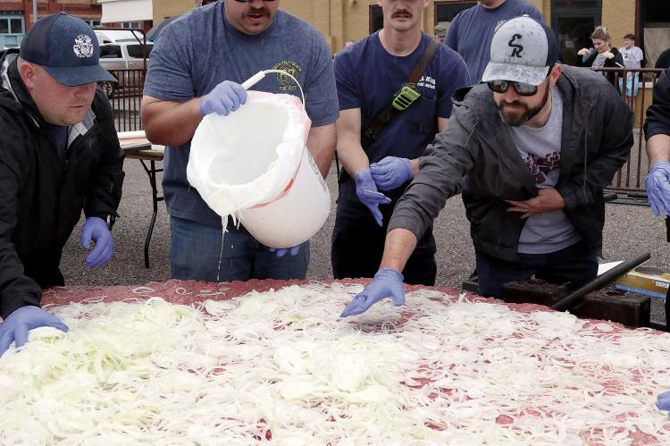 Matt Sandidge (far right) helps spread out onions on top of the hamburger meat
