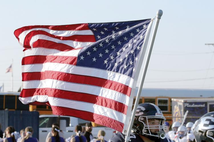 Cade Houston carries the American flag onto the field