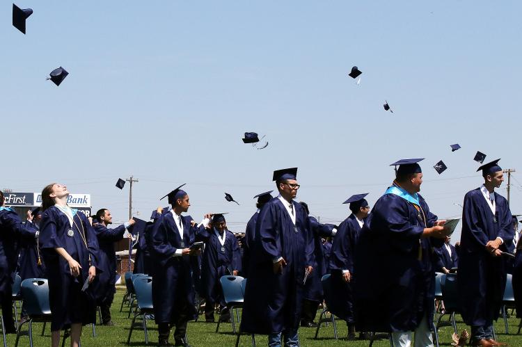 Members of the Class of 2020 toss their caps into the air