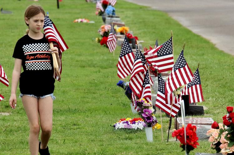 Lyzbeth Cox walks among the American flags placed on graves