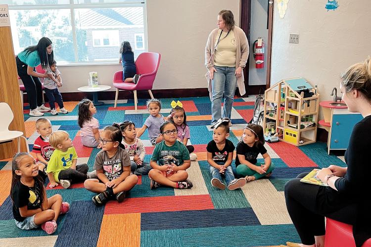 Children sit and listen as Bridget Scheffler reads them a story