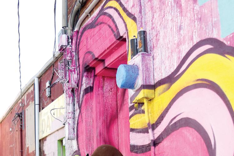 Dylan Bradway blends in a field of pink on a downtown alley wall