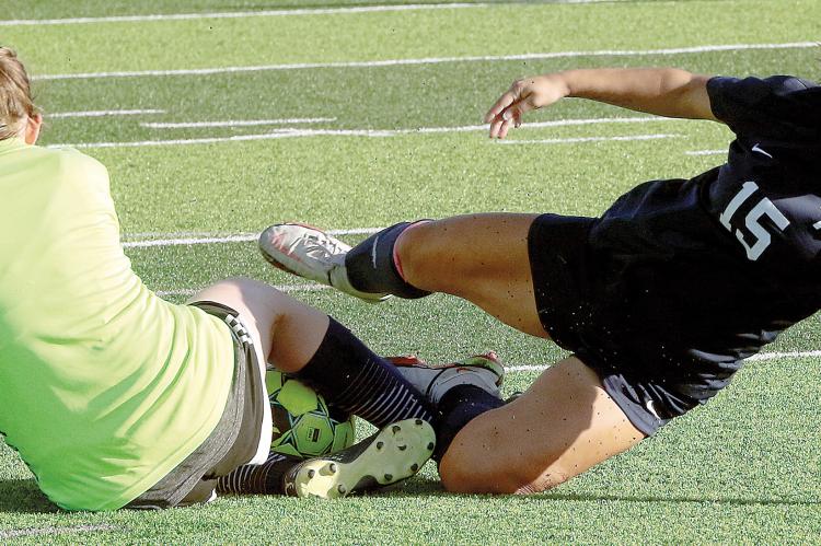 Lily Menjivar grimaces as she hits her ankle on the shin of the OKC Storm goalie