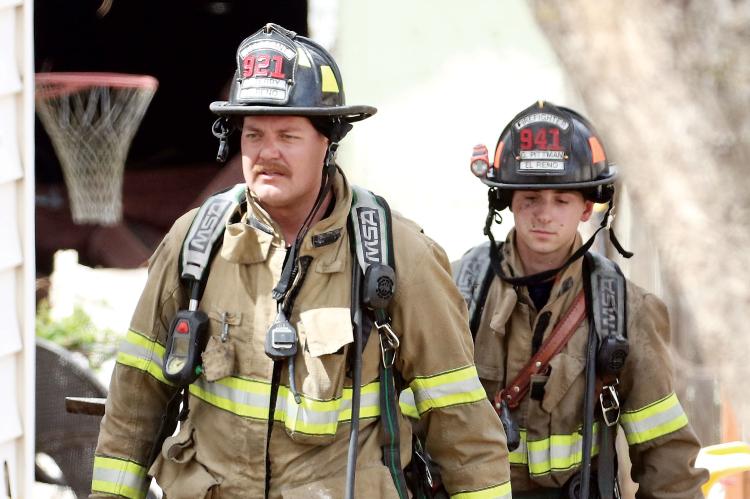 Sgt. Slade Terry and firefighter Gage Pittman carry equipment from the fire