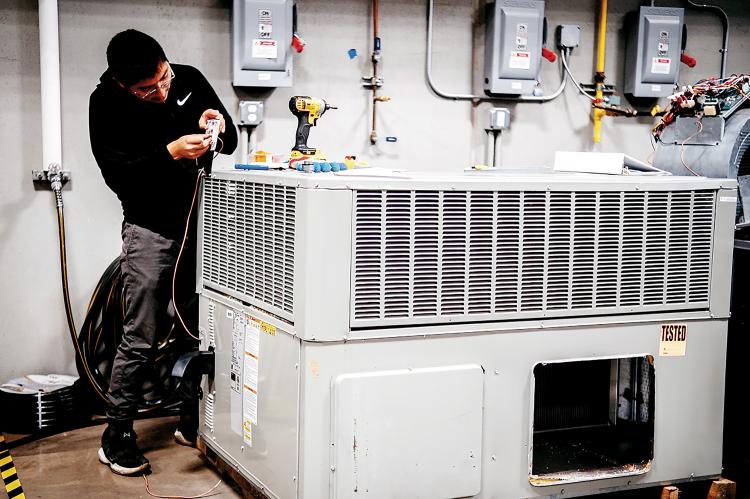 Gustavo Gonzalez installs a thermostat on a newly donated HVAC unit