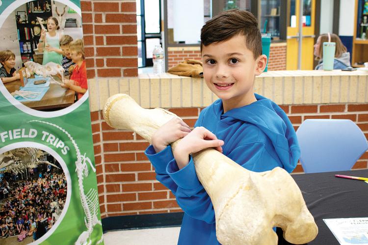 Landon Findley holds up a massive bone from an elephant