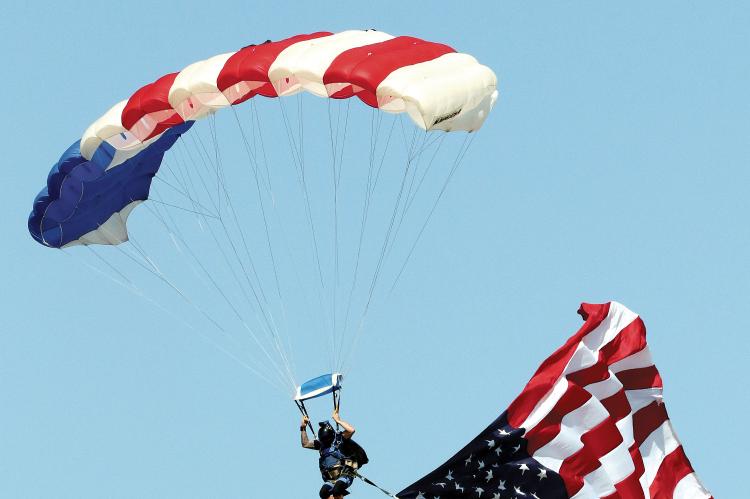 A member of Skydive Airtight glides with the American flag in tow