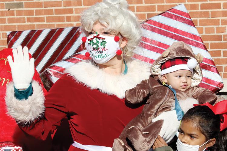 Mrs. Claus holds a young visitor dressed in a reindeer costume