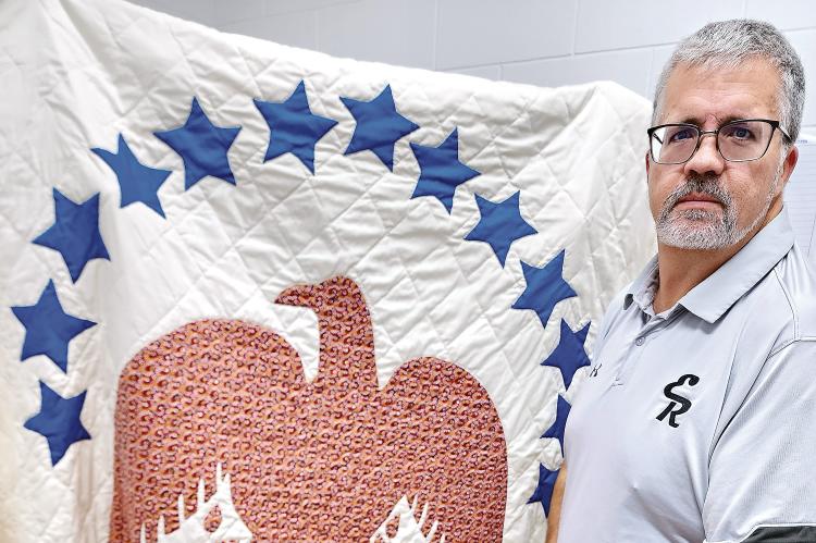 Glen Miller poses with the patriotic quilt that is being auctioned