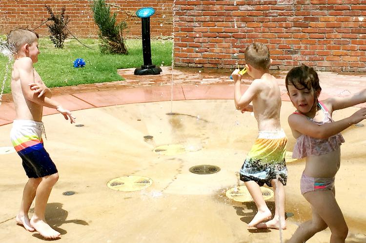 Children play in the splash pad at Youngheim Plaza