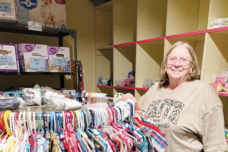 Connie Chambless stands next to children’s clothing inside the Love for the Children Center