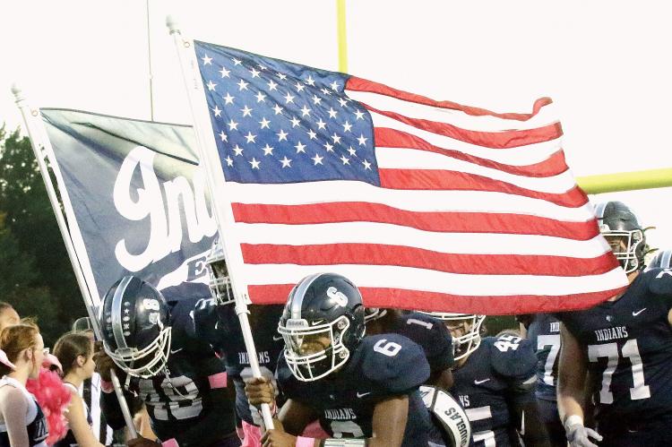 Elijah Fisher (6) carries the American flag onto the field