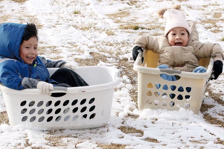 David and Asahi Paris use laundry baskets to slide down the hill