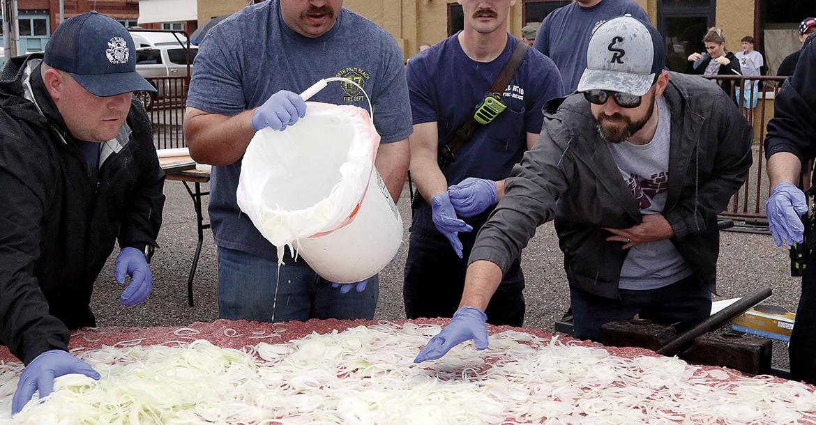 Matt Sandidge (far right) helps spread out onions on top of the hamburger meat_slideshow