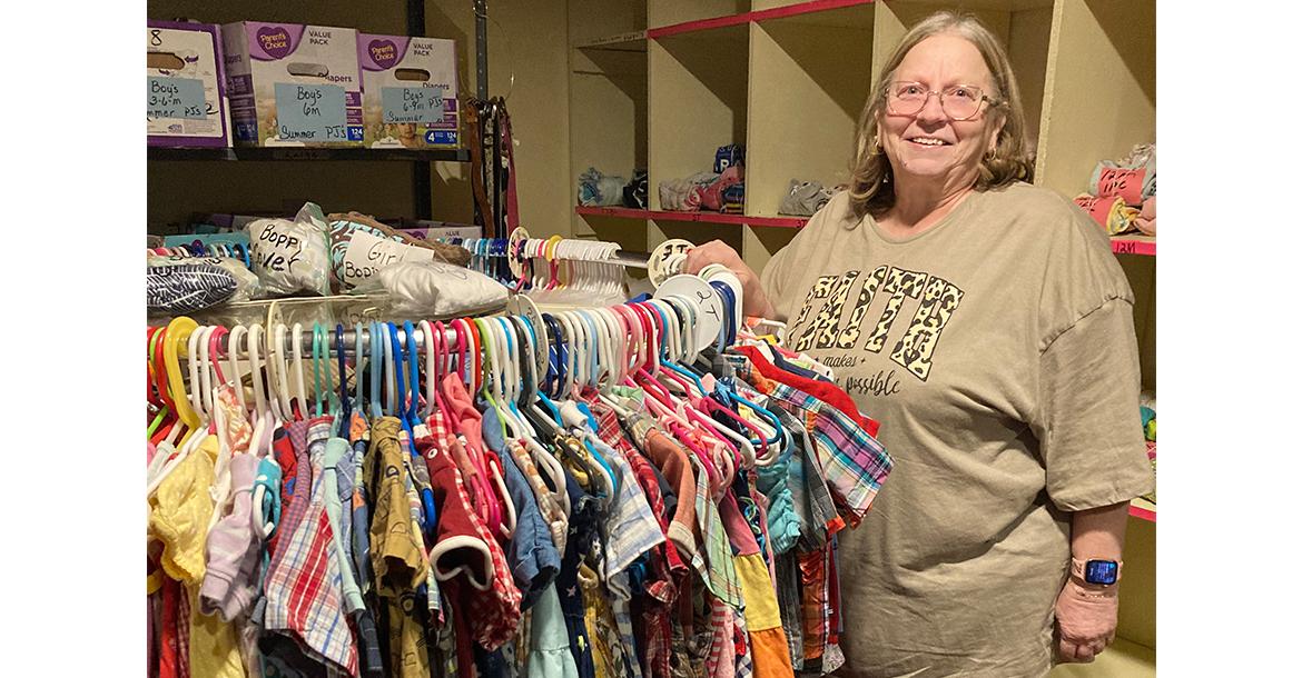 Connie Chambless stands next to children’s clothing inside the Love for the Children Center_slideshow